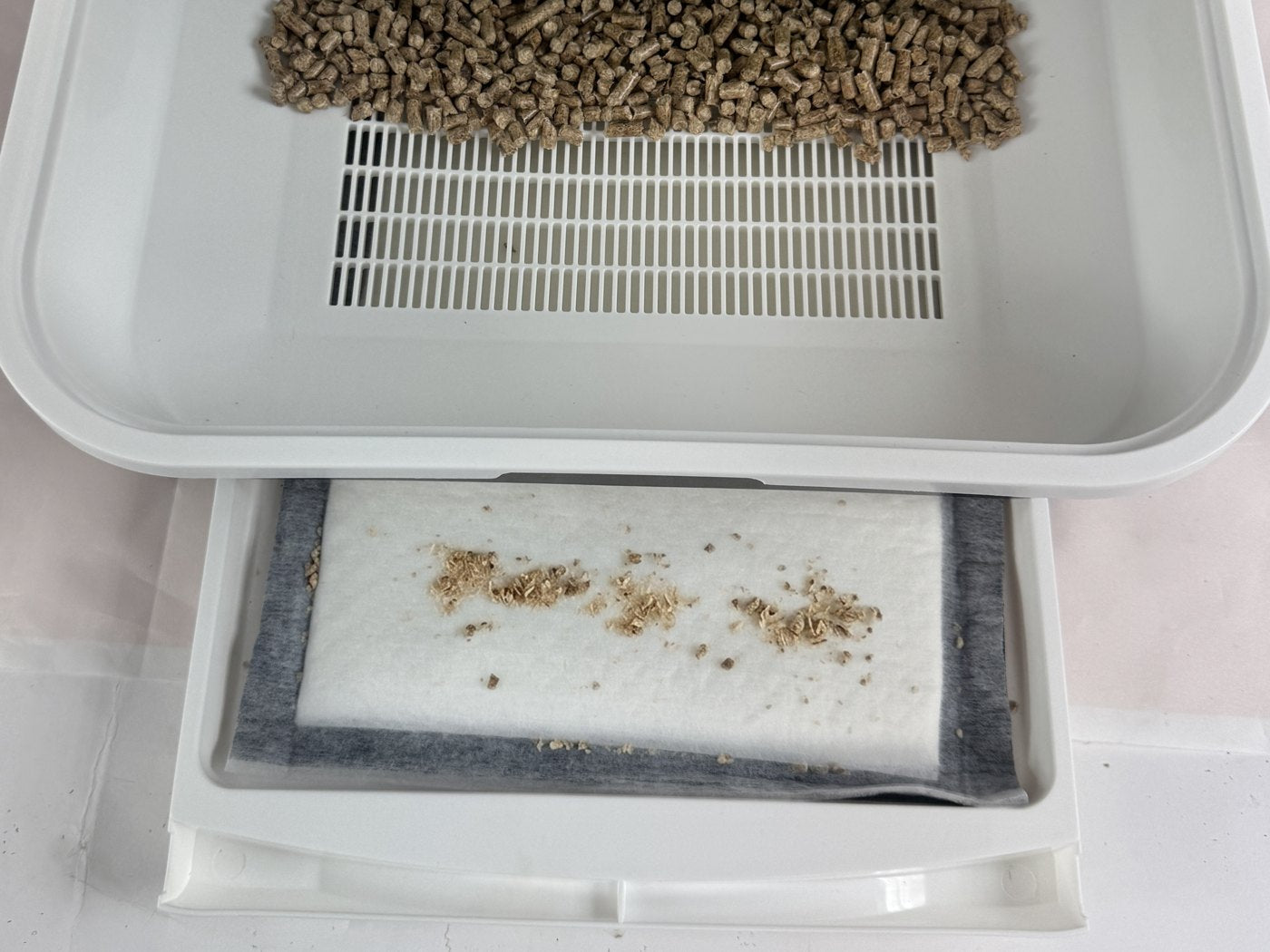 Siebrost mit Holzpellets und die Schublade mit Catpad und Sägespänen darunter